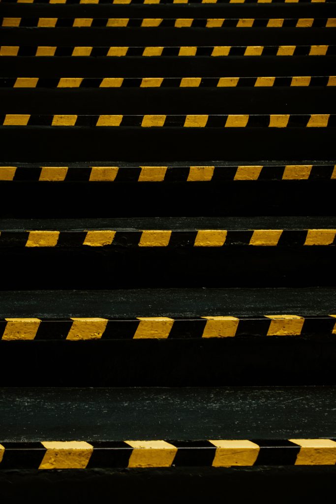 Dark stairs with bold yellow and black caution stripes create a striking visual effect.